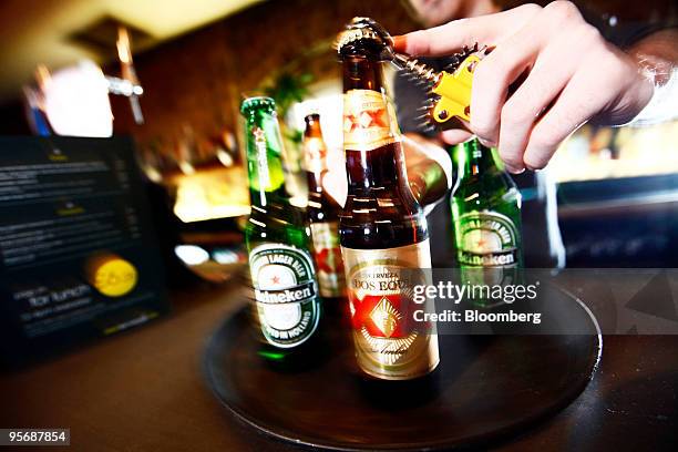 Barman opens a bottles of Dos Equis and Heineken beer at a public house in London, U.K., on Monday, Jan. 11, 2010. Heineken NV agreed to buy the beer...