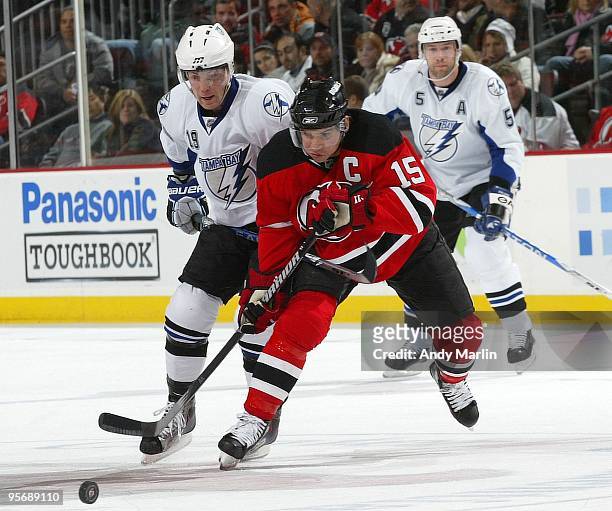 Jamie Langenbrunner of the New Jersey Devils plays the puck while being checked by Stephane Veilleux of the Tampa Bay Lightning during their game at...