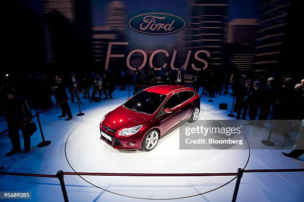 Members of the media look at the 2011 Ford Focus compact after its unveiling on day one of the 2010 North American International Auto Show in...