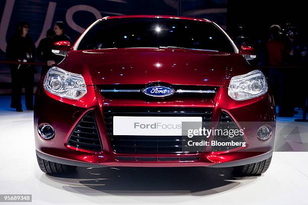 Members of the media look at the 2011 Ford Focus compact after its unveiling on day one of the 2010 North American International Auto Show in...