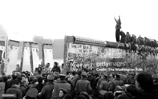 People gather near a part of the Berlin Wall that has been broken down after the communist German Democratic Republic's decision to open borders...