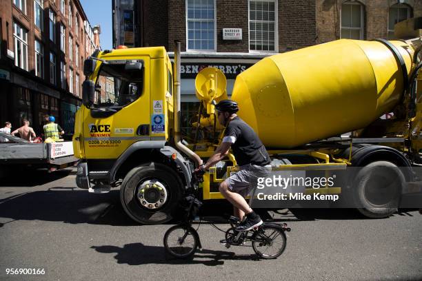 Busy street scene on Wardour Street in Soho as vehicles and pedertrians pass at the the same time including a yellow concrete mixer in London,...