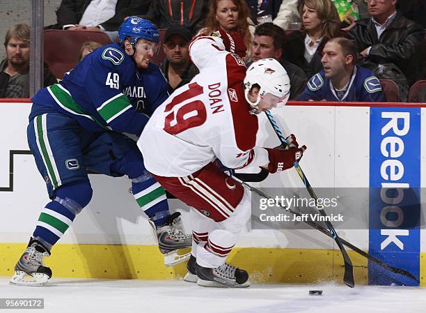 Shane Doan of the Phoenix Coyotes is checked by Alexandre Bolduc of the Vancouver Canucks during their game at General Motors Place on January 7,...