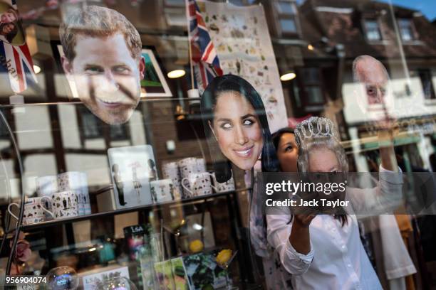 Shop worker arranges masks depicting members of the Royal Family in the window of a shop ahead of the wedding of Prince Harry and his fiance US...