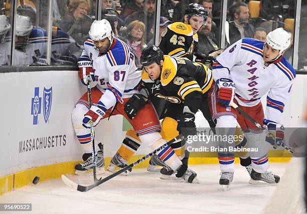 Dennis Wideman of the Boston Bruins tries to skate after the puck against Donald Brashear and Wade Redden of the New York Rangers at the TD Garden on...