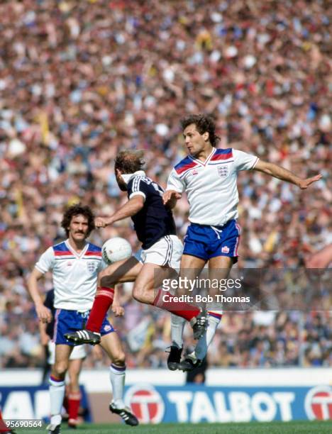 Ray Wilkins of England jumps higher than Archie Gemmill of Scotland watched by England's Terry McDermott during the Home International Championship...