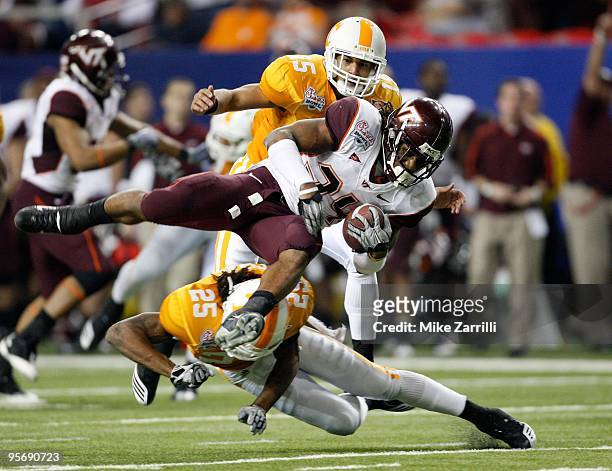 Tailback Ryan Williams of the Virginia Tech Hokies is tackled by defensive back Art Evans of the Tennessee Volunteers while Evans' teammate and...
