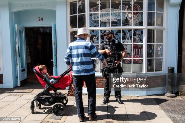 An armed police officer speaks to a member of the public ahead of the wedding of Prince Harry and his fiance US actress Meghan Markle on May 10, 2018...