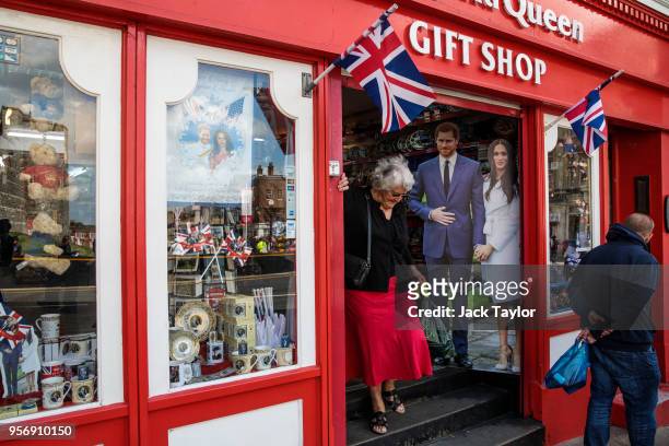 Woman leaves a gift shop with a cardboard display of Prince Harry and his fiance US actress Meghan Markle on May 10, 2018 in Windsor, England. St...