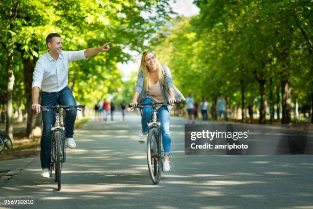 casual happy young tourist couple cycling through alley - prater wien stock pictures, royalty-free photos & images