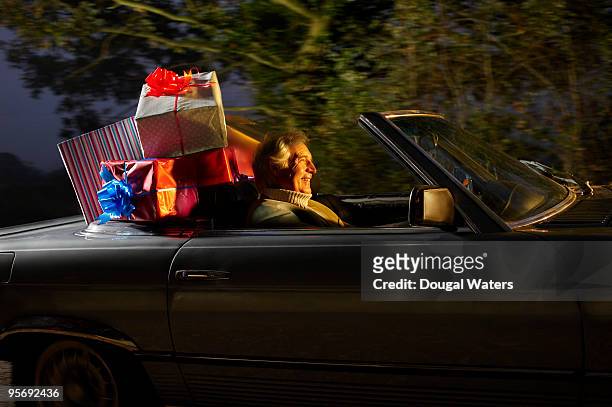senior man driving car full of presents. - christmas driving stock pictures, royalty-free photos & images