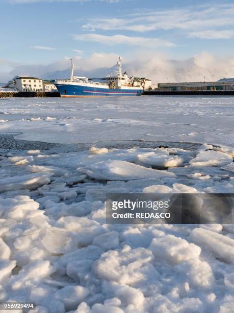 The frozen harbour of the small town Hoefn during winter. In the background the mountains of Stokksnes. Europe. Northern europe. Iceland. February.