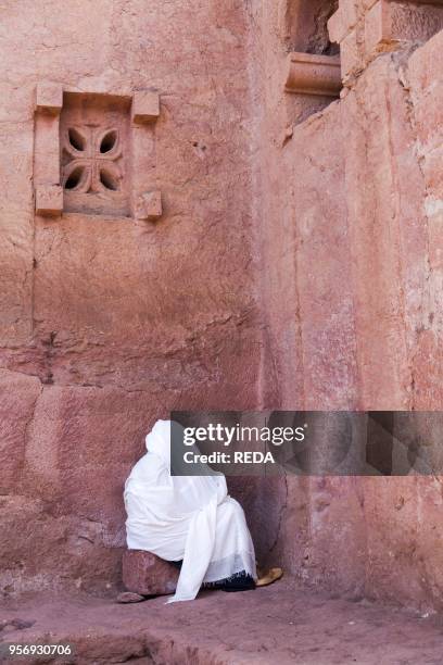 The rock-hewn churches of Lalibela in Ethiopia. Pilgrim praying in front of a church. The churches of Lalibela have been constructed in the 12th or...