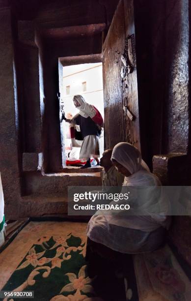 The rock-hewn churches of Lalibela in Ethiopia. Pilgrim praying in front of a church. The churches of Lalibela have been constructed in the 12th or...