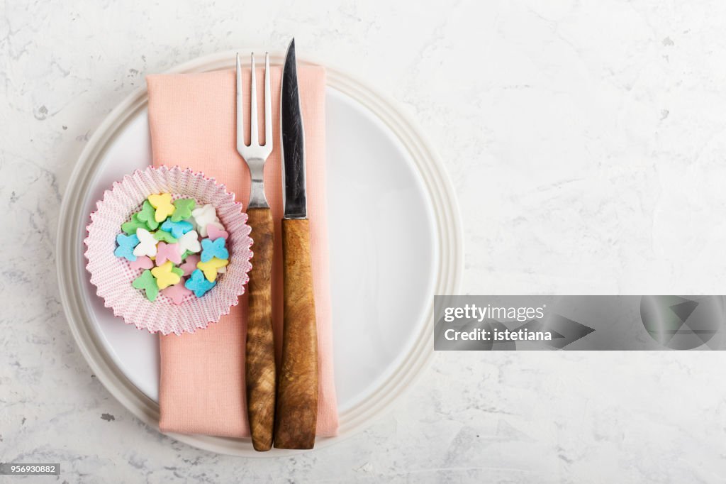 Place setting with empty cupcake case on light grey background