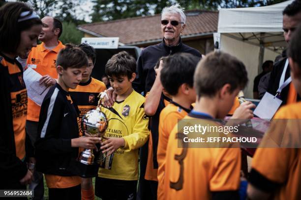 Aime Jacquet, former coach of French national football team and the 1998 world champion, delivers a trophy to a young football players at the end of...