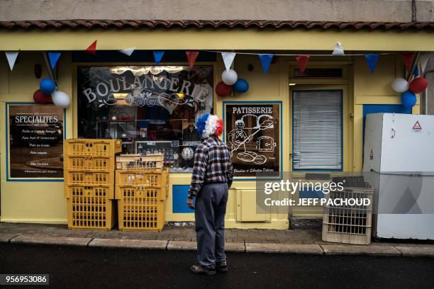 Man passes by a bakery decorated with French national colors, on May 10, 2018 in Sail-sous-Couzan, western France, on the day the French national...
