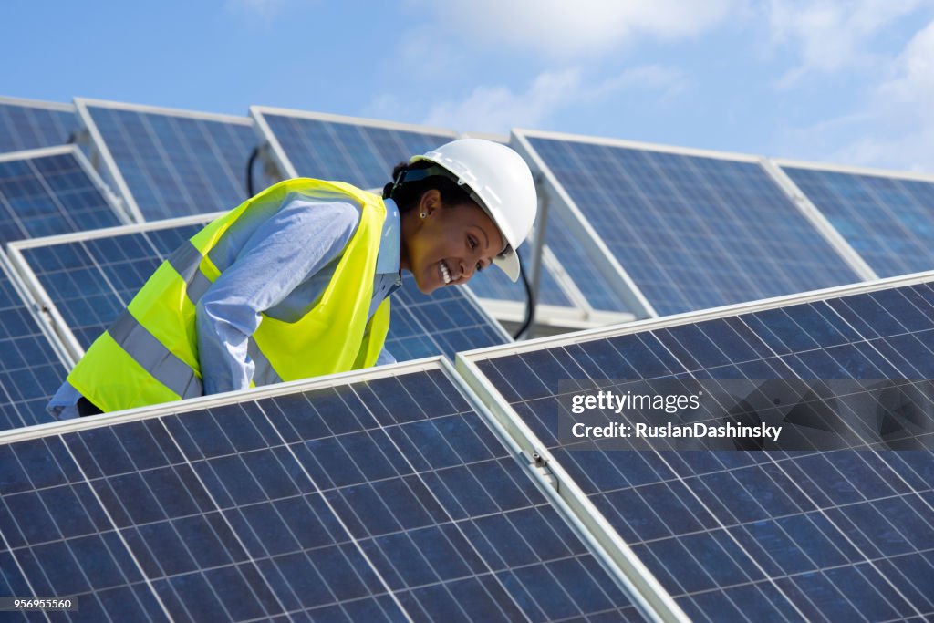 Mujer Ingeniero de energía trabajando en un techo con paneles solares.