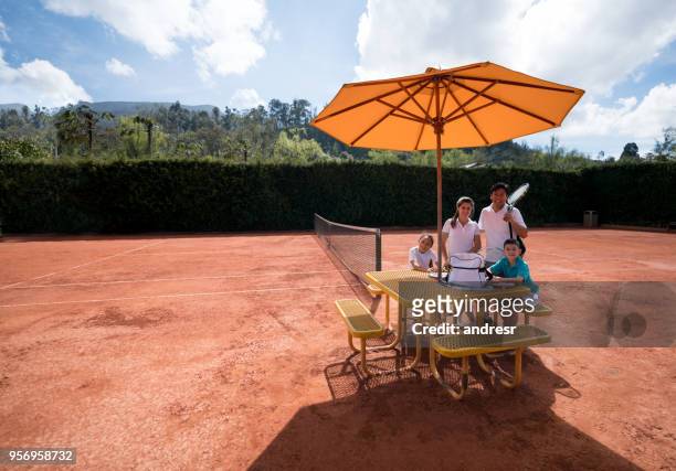 portret van de familie zittend op tafel op de tennisbaan kijken camera glimlachen - women's table tennis stockfoto's en -beelden