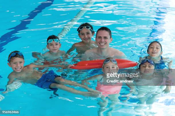 zwemleraar met zijn studenten in de pool die alle camera erg blij kijken terwijl leraar een redding houdt buoy - pool boat stockfoto's en -beelden