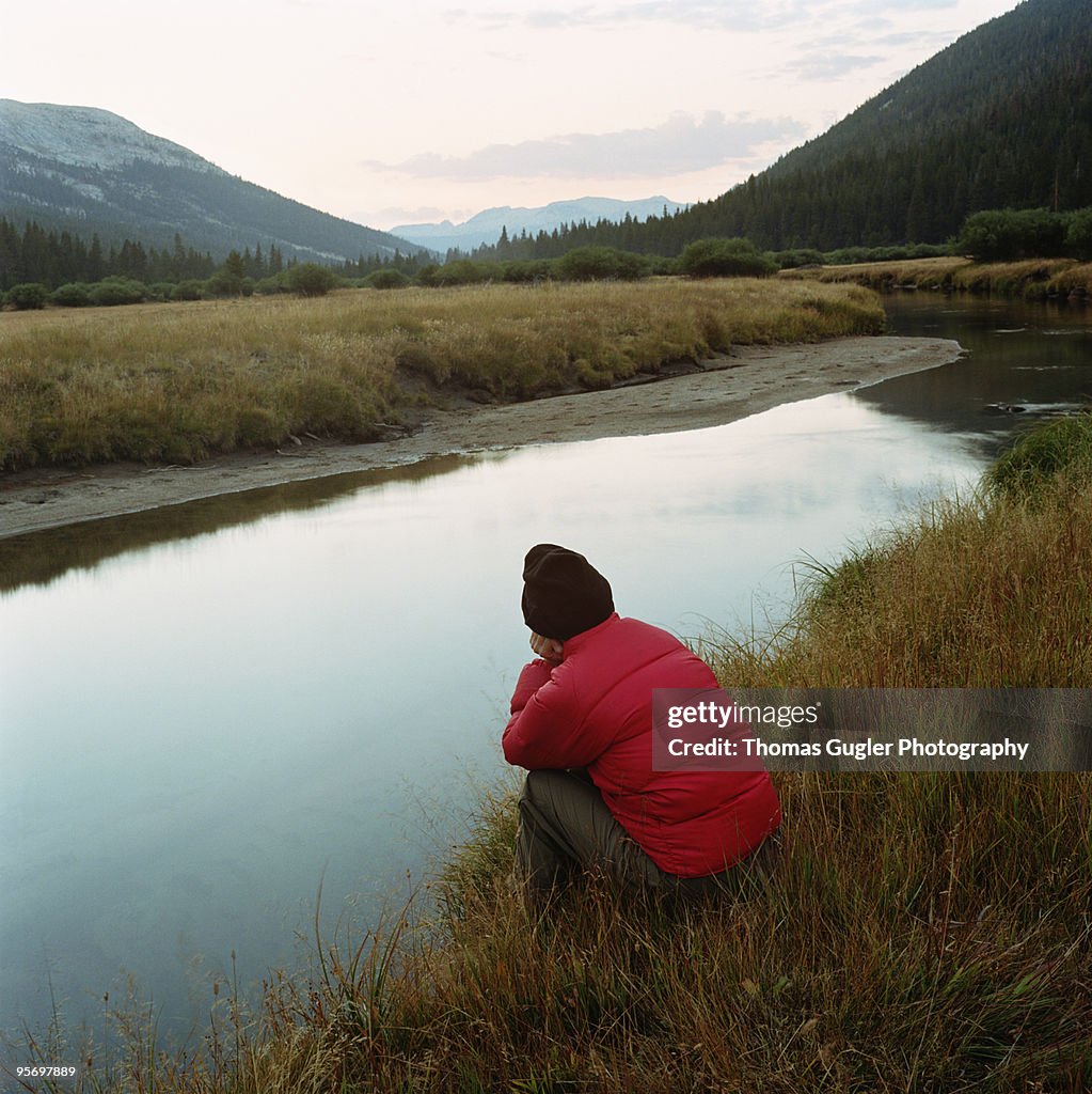 Woman crouched down near mountain stream