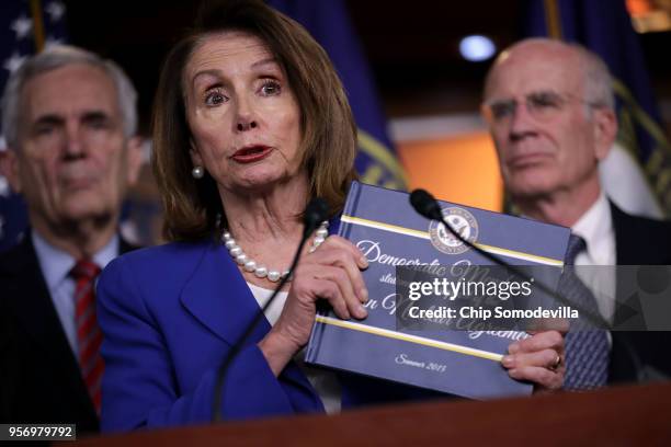 House Minority Leader Nancy Pelosi holds up a book of statements of support for the 2015 Iran nuclear deal during a news conference with fellow...