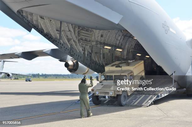 Air Force loadmaster directing the loading of an M1152 Humvee onto a C-17 Globemaster III, May 7, 2018. Image courtesy Staff Sgt. Chris McCullough /...