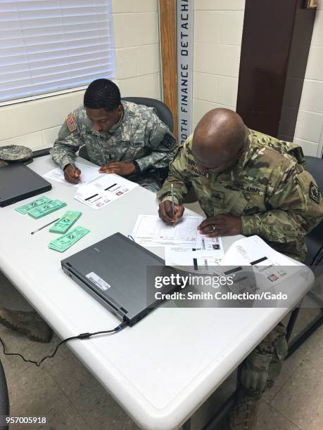 Photograph of Finance Corps members Cadet Ray Carter and Staff Sergeant Bobby Johnson filling out financial forms as part of disbursement training...