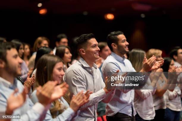 gente feliz en un concierto en un teatro haciendo una ovación de pie y aplaudiendo - ovación de pie fotografías e imágenes de stock