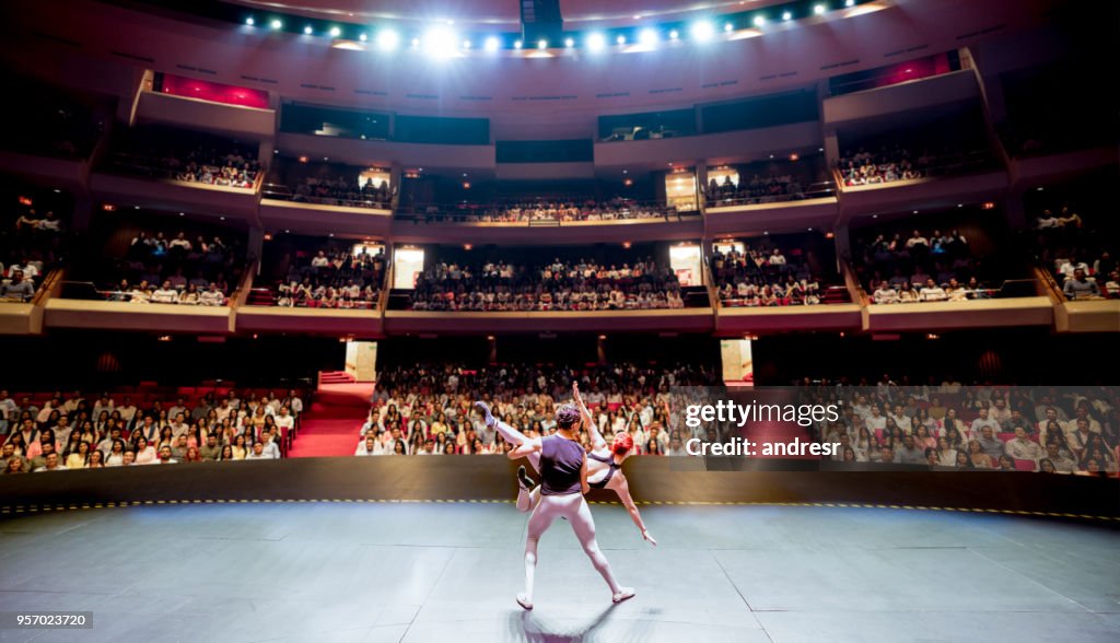 Rear view of ballet dancers performing on stage for a large public