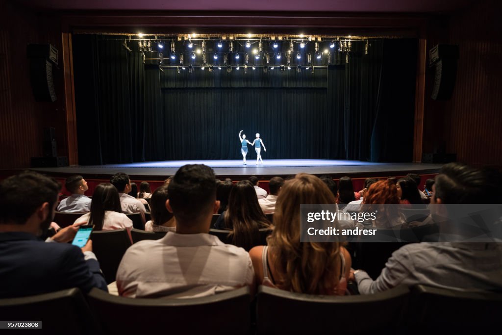 Personas en un teatro viendo un ensayo de artes escénicas, ballet