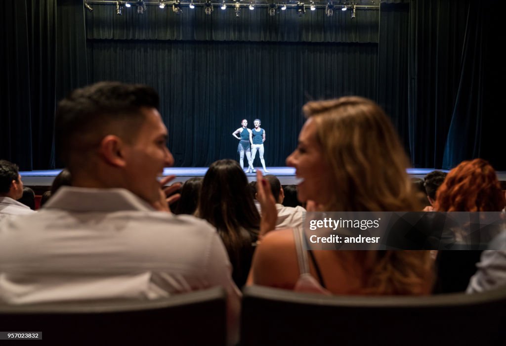 Young couple on a date at ballet applauding and looking at each other smiling