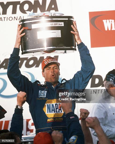 Michael Waltrip hoists the Harley J. Earl Daytona 500 trophy into the air after defeating his teammate, Dale Earnhardt Jr., in the Daytona 500. It...