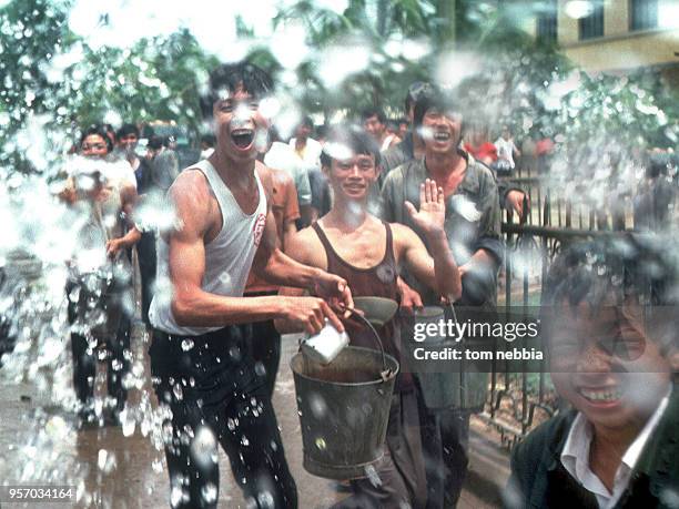 View of a group of young men laughing as they throw water towards the camera during the Water Splashing festival, Xishuangbanna, Yunnan province,...