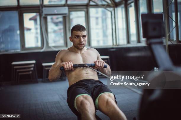 guy training on rowing machine - barbell row stock pictures, royalty-free photos & images