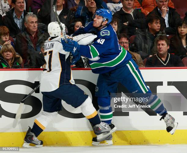 Alexandre Bolduc of the Vancouver Canucks and Francis Bouillon of the Nashville Predators have the same idea as they check one another during their...