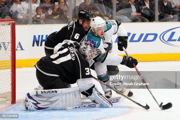 Devin Setoguchi of the San Jose Sharks reaches for the puck outside the crease against Erik Ersberg and Sean O'Donnell of the Los Angeles Kings...