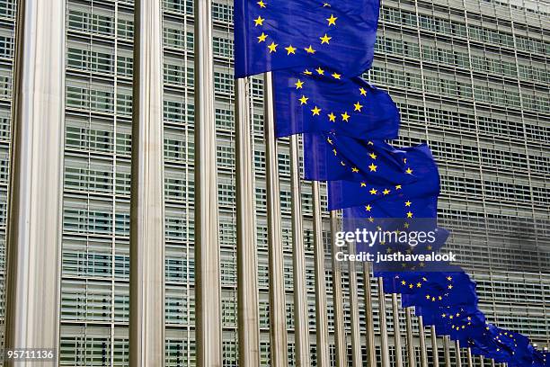 eu flags in brussels against building - europees-parlement stockfoto's en -beelden