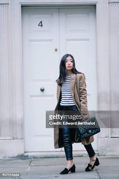 Fashion blogger Maymaryb wears a beige coat, a black and white striped top, black leather pants, a Chanel Jumbo bag, Gucci shoes, in the streets of...