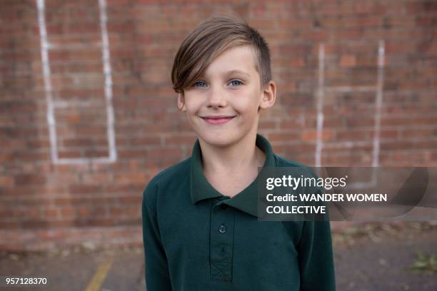portrait of australian public school boy in  the playground smiling against red brick wall - guidelines of cultural politics stock pictures, royalty-free photos & images