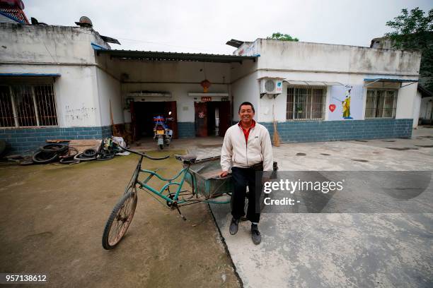 This photo taken on April 24, 2018 shows Yang Jian sitting on his bicycle leftover from the 2008 Sichuan earthquake as he poses for a picture in...