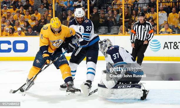 Connor Hellebuyck of the Winnipeg Jets makes the save against Austin Watson of the Nashville Predators as Dustin Byfuglien defends in Game Seven of...