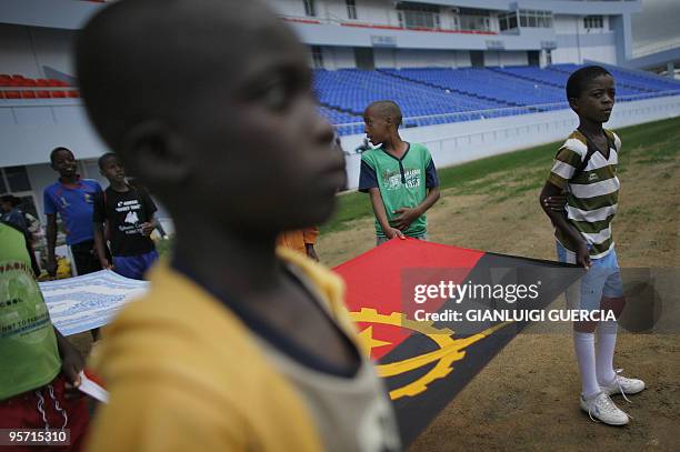 Angolan kids hold an Angolan flag as they rehearse at the Tundavala Stadium on January 11, 2010 in Lubango. Lubango is one of the four city hosting...