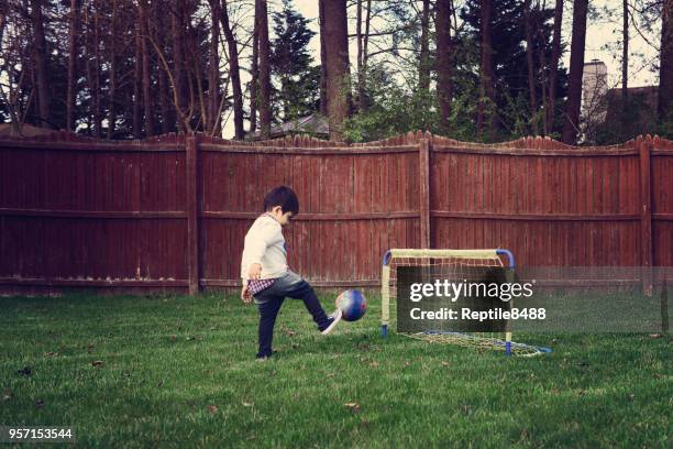 toddler boy playing soccer in the backyard - baby kicking stock pictures, royalty-free photos & images