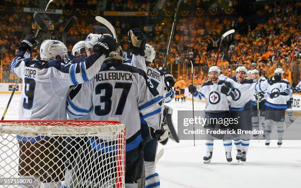 Andrew Copp, and Connor Hellebuyck of the Winnipeg Jets celebrate with their teammates after a 5-1 Jets Victory in Game Seven of the Western...