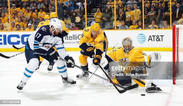 Juuse Saros of the Nashville Predators makes the save against Adam Lowry of the Winnipeg Jets as Mattias Ekholm defends in Game Seven of the Western...