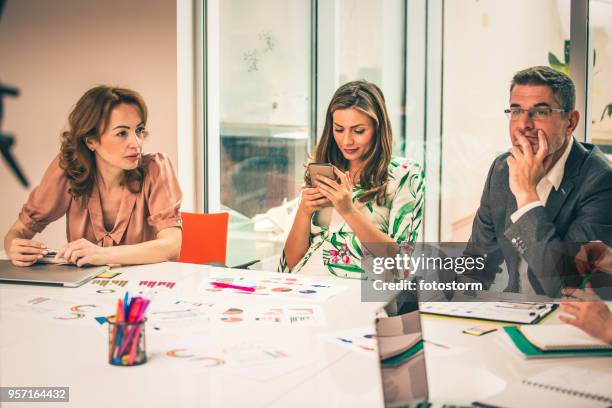 woman texting during business meeting - boring meeting stock pictures, royalty-free photos & images