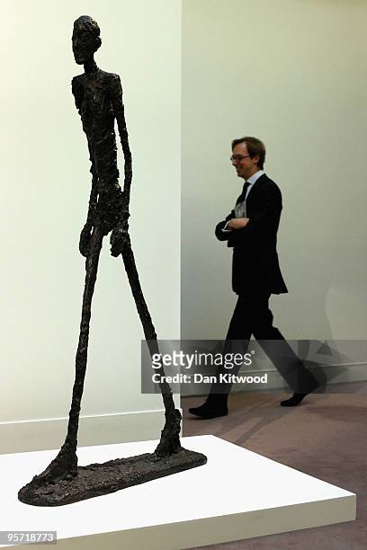 An auction house employee walks past a work entitled 'Homme qui marche' by Alberto Giacometti at Sotheby's auction house on January 12, 2010 in...