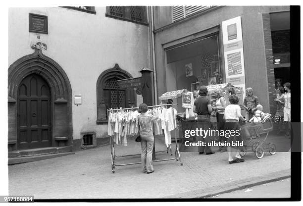 Zum Sommerausklang hat ein Bekleidungsgeschäft neben dem Sterbehaus Martin Luthers in Eisleben Ständer mit Blusen und Kleidern auf den Gehweg...