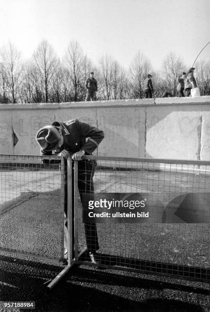 Ein DDR-Grenzsoldat überprüft an der Berliner Mauer am Brandenburger Tor einen Absperrzaun, aufgenommen am in Berlin. Seit dem 22. Dezember 1989 ist...